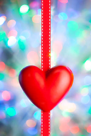 Red heart and ribbon on blurred colorful abstract backgroundの写真素材
