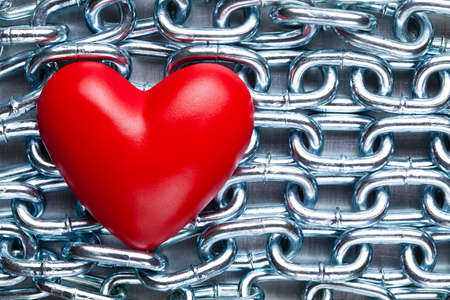 Red plastic heart on steel chains backgroundの写真素材