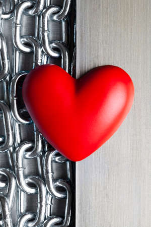 Red heart on steel chains and aluminum plate backgroundの写真素材