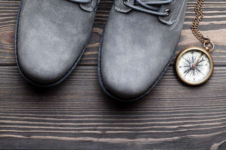 Pair of hiking boots and compass on wooden tableの写真素材