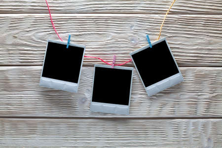 Three vintage photo frames on colored rope and white wooden backgroundの写真素材