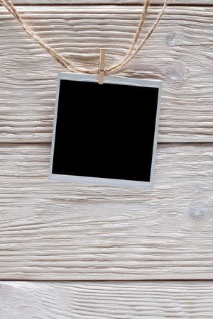 Photo frame with empty space on rope and wooden wall backgroundの写真素材
