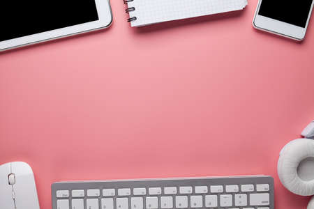 Mobile phone, tablet, computer keyboard, headphones and notebook on pink backgroundの写真素材