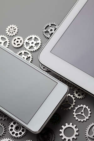 Mobile phone and small gears on gray tableの写真素材
