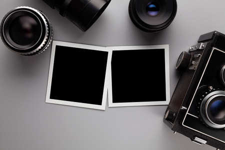 Photographic template - paper photo frames with blank space, lens and camera on gray tableの写真素材