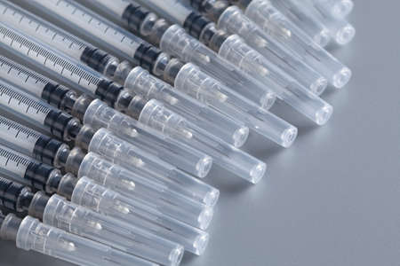 Many syringes with needles on a gray background