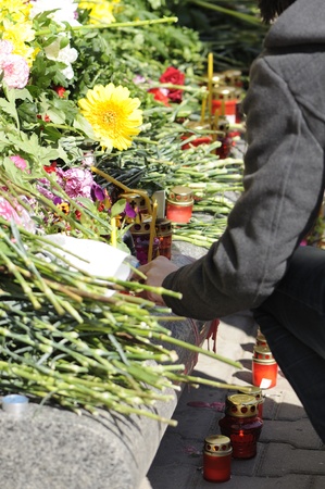 MINSK, BELARUS - APRIL 12, 2011: A woman lights a candle near Oktyabrskaya metro station after a terrorist attack on April 11, 2011 in Minsk, Belarusのeditorial素材