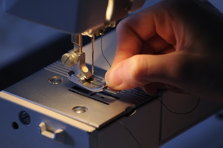 Hand of Seamstress Threading Sewing Machine