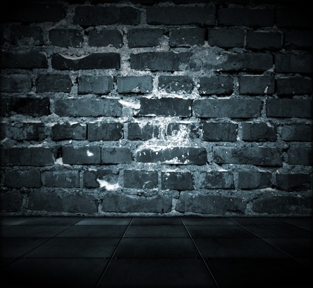 A dark grungy room with a cracked brick wall and tiled floorの写真素材