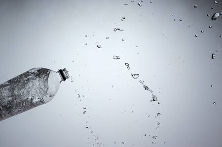 Dynamic shot of water spilling out of plastic bottleの写真素材