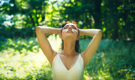 Beauty romantic girl enjoying nature in outdoors. Happy young woman in casual short dress relaxing on meadow in the middle of forest.の写真素材