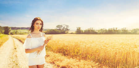 Beauty romantic girl enjoying nature in outdoors. Happy young woman in white shorts holding the ears...