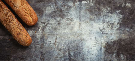Fresh bakery food. Crusty loaves of mixed breads and buns and ears of wheat on rustic table background. Top view and copy space for text. Banner wide format.の写真素材
