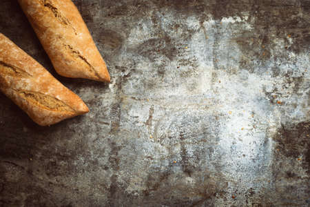 Fresh bakery food. Crusty loaves of mixed breads and buns and ears of wheat on rustic table background. Top view and copy space for text.の写真素材