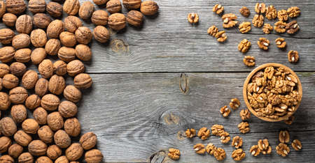 Fresh walnut kernels and whole walnuts in a bowl on rustic old wooden table. Healthy organic food, BIO viands, natural background. Copy space for your advertising text message.の写真素材