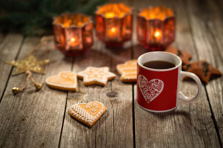 Homemade Christmas mulled wine punch with gingerbread on wooden rustic table. Burning candles in...