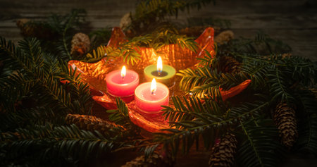 Christmas decoration with burning candles on dark background with branch with needles. Close-up and shallow depth of field. Christmas holidays and New Year theme.の写真素材