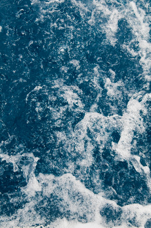 Bubble sea water surface background close-up. Rapid blue splashing water texture with white foam. Caribbean lifestyle themes.の写真素材