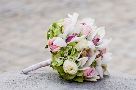 Bridal bouquet laying on stone block. Beautiful romantic white and pink wedding flowers with copy space and blurred background. Close-up.の写真素材