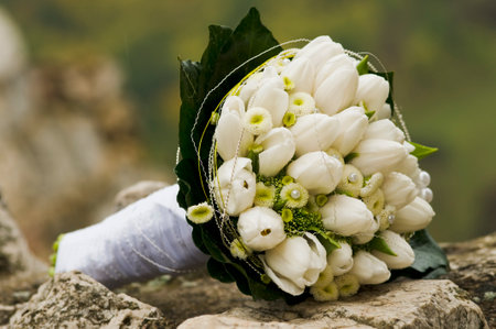 Bridal bouquet laying on stone block. Beautiful romantic white wedding flowers with copy space and blurred background. Close-up.の写真素材
