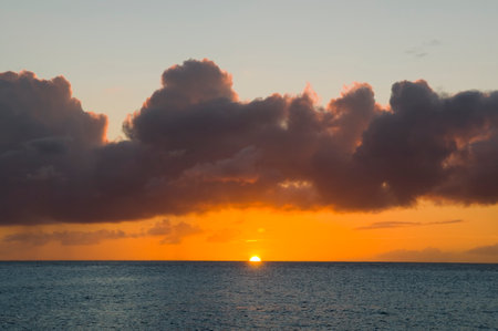 Sunset over Caribbean sea. Deep ocean view with waves and dark clouds. Relaxing seascape, endless sea, tropical waters background. Blue seas and orange skies separated by a far away horizon.の写真素材