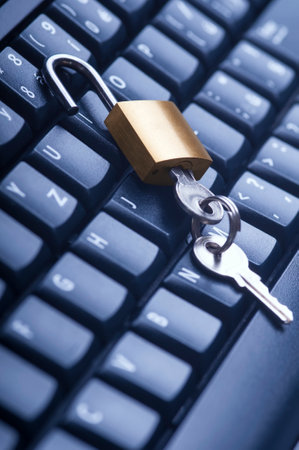 Unlocked metal padlock with keys on blue computer keyboard. Data and password protection, internet...