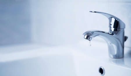 Water tap, stainless steel faucet. Drop drip in bathroom with sink. Liquid leak in modern clean house interior. Resources consumption concept.の写真素材