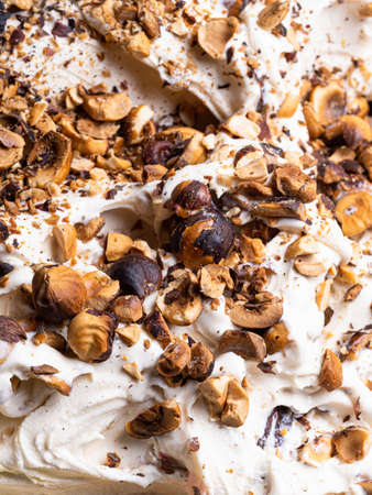 Frozen Hazelnut flavour gelato - full frame detail. Close up of a white creamy surface texture of Ice cream covered with pieces of nuts.の写真素材