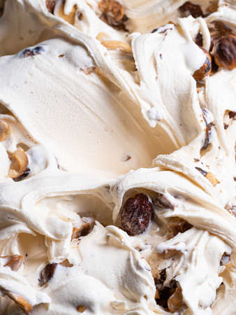 Frozen Hazelnut flavour gelato - full frame detail. Close up of a white creamy surface texture of Ice cream filled with pieces of nuts.の写真素材