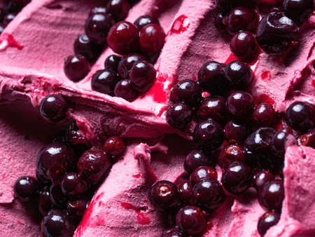 Frozen Black Elderberry flavour gelato - full frame detail. Close up of a pink surface texture of Ice cream covered with pieces of dark red fruit.の写真素材