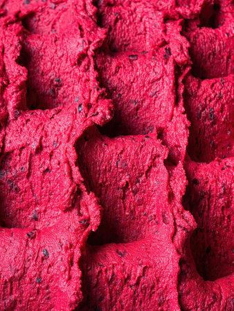 Frozen Black Currant flavour gelato - full frame detail of sorbet. Close up of a red surface texture of Ice cream filled with pieces of mixed fruit.の写真素材