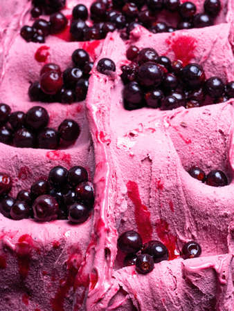 Frozen Black Elderberry flavour gelato - full frame detail. Close up of a pink surface texture of Ice cream covered with pieces of dark red fruit.の写真素材