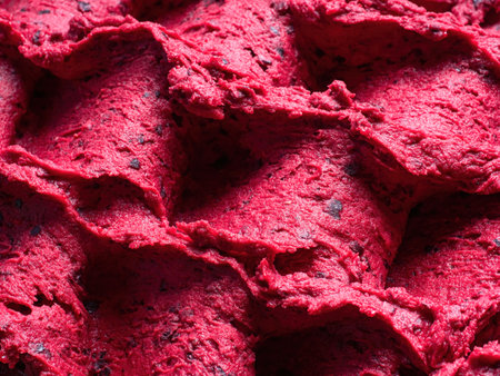 Frozen Black Currant flavour gelato - full frame detail of sorbet. Close up of a red surface texture of Ice cream filled with pieces of mixed fruit.の写真素材