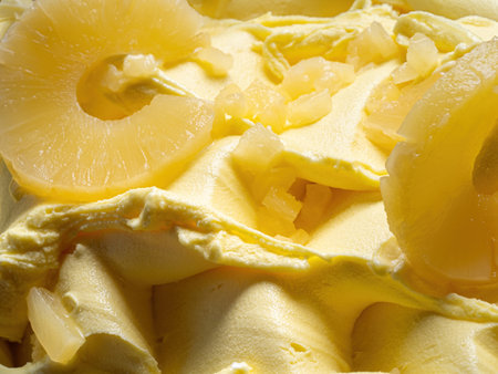 Frozen Pineapple flavour gelato - full frame detail. Close up of a yellow surface texture of Ice cream covered with pieces of fruit.の写真素材