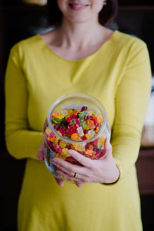 Woman offers gummy bears from glass jarの写真素材