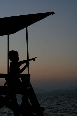 A child on a lookout tower at sunset on the beach...の写真素材