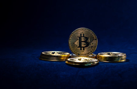 Golden bitcoin in the middle of pile, Bitcoin with blue graph on black background. Crypto currency conceptの写真素材