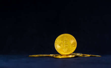 Golden bitcoin in the middle of pile, Bitcoin with blue graph on black background. Crypto currency...