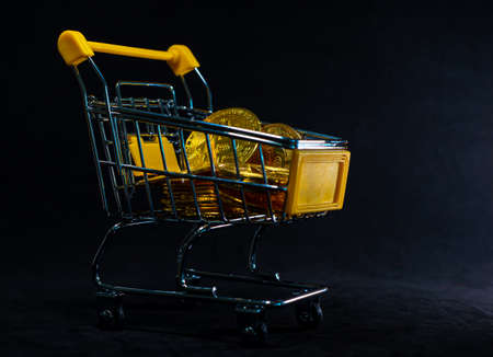 Yellow trolley full of Golden Bitcoin  on black background. Digital Business and finance concept.の写真素材