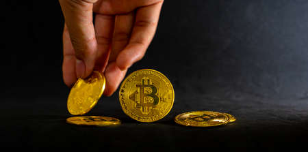 Golden bitcoin on pile, Bitcoin falling with black background. Currency exchange and Digital money...