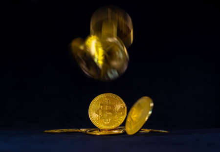 Golden bitcoin on pile, Bitcoin falling with black background. Currency exchange and Digital money concept.の写真素材