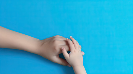 Children's hands holding each other on a blue background with copy spaceの素材