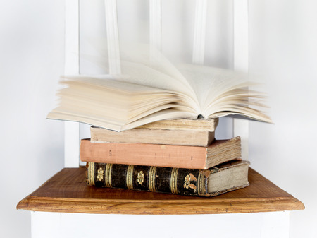 old books on a white chair and white backgroundの写真素材