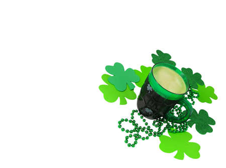 A green plastic party mug for St. Patrick's Day stands with foaming beer among a pile of green beads...