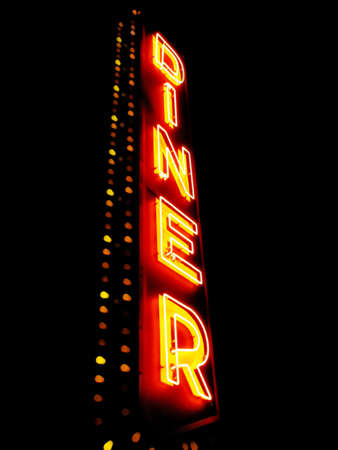 A large neon sign says "diner" against a black night sky.の写真素材