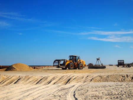 Various pieces of machinery and vehicles are scattered about on a portion of beach that is being replenished の写真素材