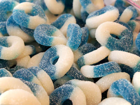 Closeup in a bin of blue raspberry or blueberry gummy fruit ring candy with crystallized sugar coating の写真素材