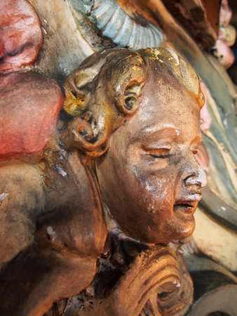 Detail of an antique cherub face carving with cracks, fading, and other signs of age and nostalgia.fの写真素材
