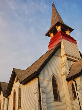 A vintage church steeple atop an old traditional church against a blue sky background.の写真素材