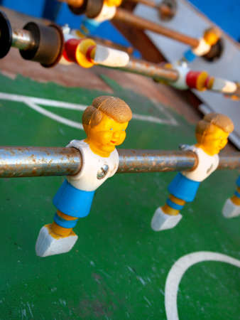 Closeup on a plastic foosball player on a control stick on a rusty old game table.